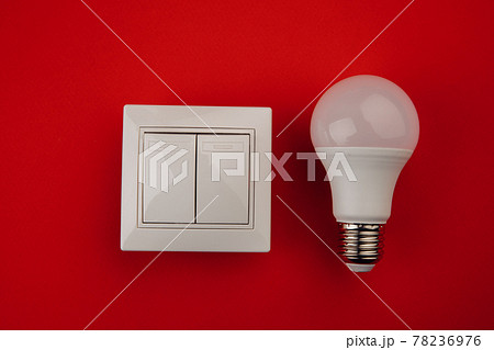 Light bulb and white switch on red background Light bulb and white switch on red background 78236976