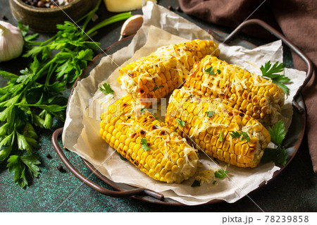 Summer vegan dinner or snacks. Grilled corn with garlic butter, served with cheese on a dark stone table top. Summer vegan dinner or snacks. Grilled corn with garlic butter, served with cheese on a dark stone table top. 78239858