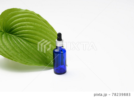 blue glass transparent bottle with a pipette on the background of a green leaf 78239883