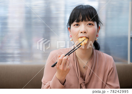 鶏の唐揚げを食べる女性 78242995
