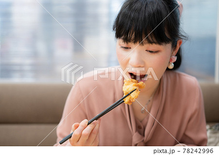 鶏の唐揚げを食べる女性 78242996