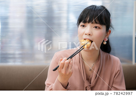 鶏の唐揚げを食べる女性 78242997