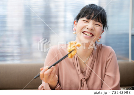 鶏の唐揚げを食べる笑顔の女性 78242998
