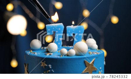 Birthday cake number 77 stars sky and moon concept, blue candle is fire by lighter. Copy space on right side of screen. Close-up Birthday cake number 77 stars sky and moon concept, blue candle is fire by lighter. Copy space on right side of screen. Close-up 78245332