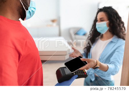 Black man holding POS machine client paying with smartphone Black man holding POS machine client paying with smartphone 78245570