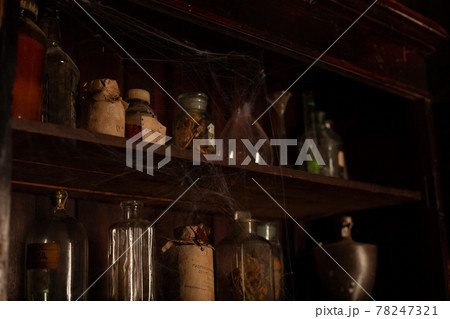 Halloween background Shelves with alchemy tools Skull spiderweb bottle with poison candles Halloween background Shelves with alchemy tools Skull spiderweb bottle with poison candles 78247321