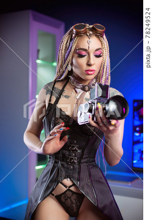portrait of a sexy woman with dreadlocks in a corset posing sexy with a retro camera portrait of a sexy woman with dreadlocks in a corset posing sexy with a retro camera 78249524