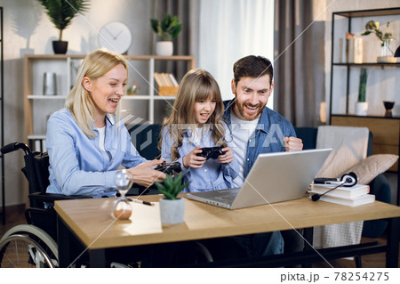 Disabled woman playing games with daughter and husband Disabled woman playing games with daughter and husband 78254275
