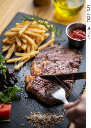 cutting steak with knife and fork on black plate cutting steak with knife and fork on black plate 78254381