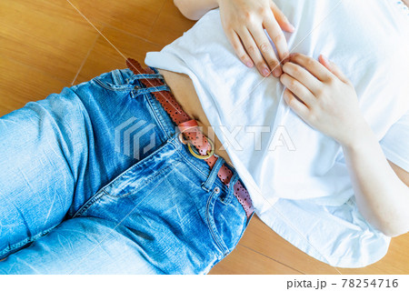 お腹を出して寝転がる女性の写真。だらしない女性のイメージ。 78254716