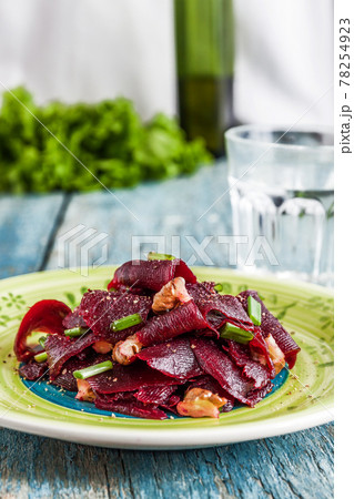 On a bright ethnic plate is a vegetarian lean beet salad, green shnit-onion, gritsy nut. Top view. The concept of simple healthy food 78254923
