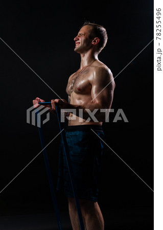 Man on black background keeps dumbbells pumped up in fitness biceps torso, arm fitness lifting heavy, healthy Attractive metal, human fit With a ribbon in hand, the fitness gum is black 78255496