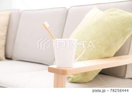 ソファの肘掛けに置かれたハブラシの入ったカップ 78256444