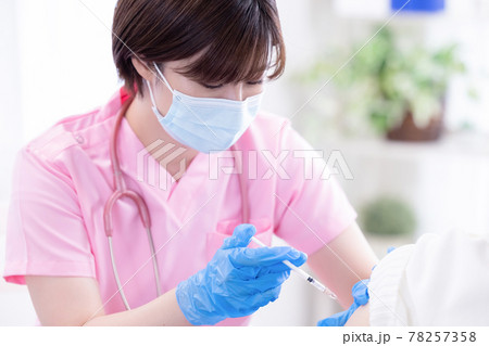 医療　コロナウイルスワクチンを高齢者に打つ女性医師 78257358