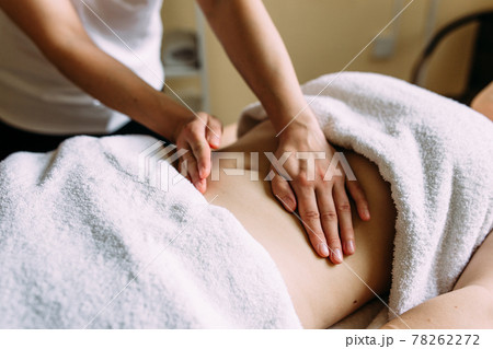 The masseur gives a massage to the female belly at the spa. 78262272