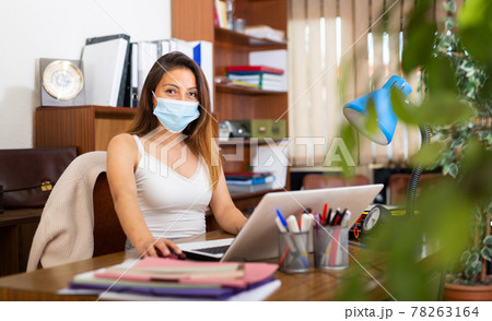 Hispanic businesswoman in face mask sitting in office Hispanic businesswoman in face mask sitting in office 78263164