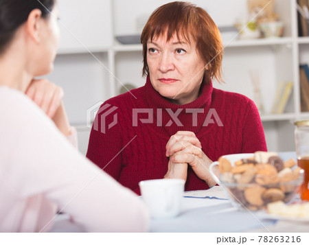 Unhappy adult female talking with daughter at table Unhappy adult female talking with daughter at table 78263216