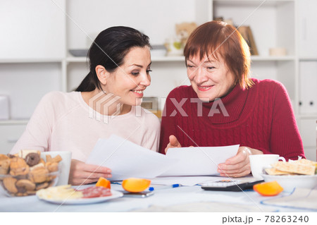 Happy women with documents sitting at table 78263240