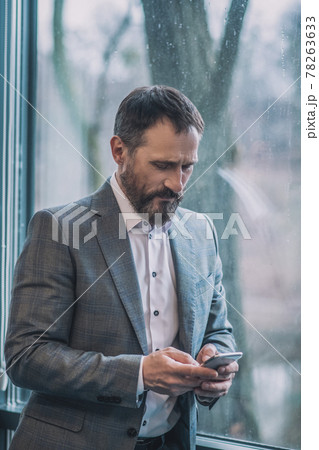Man staring intently into smartphone near window 78263633