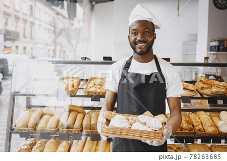 African American baker holding tray of bread in bakery African American baker holding tray of bread in bakery 78263685