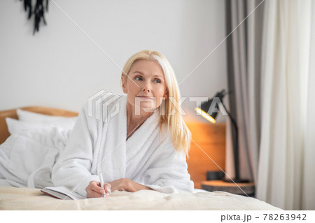 A cute woman lying on the bed and making notes A cute woman lying on the bed and making notes 78263942