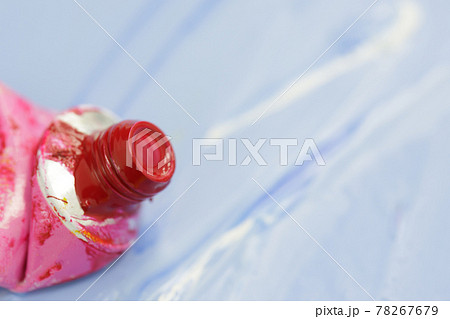 tube of watercolor red paint against the background of blue painted sheet 78267679