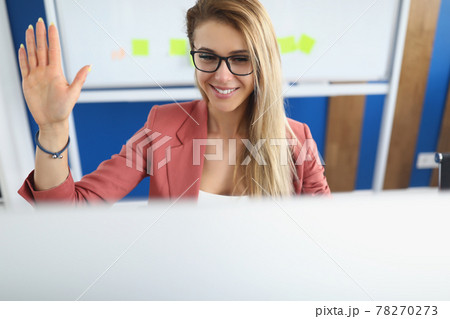 Young woman waving hand at computer screen in office Young woman waving hand at computer screen in office 78270273