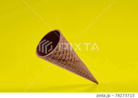 Empty, crispy wafer cone for ice cream against yellow background. Concept of food, treats. Mockup, template for your advertising and design. Close up 78273715