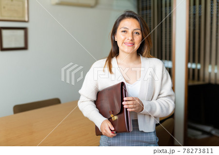 Portrait of woman holding briefcase in hands in modern office 78273811