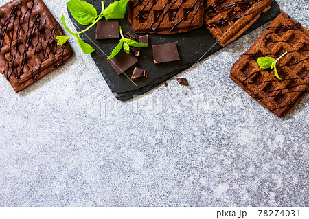 Homemade brownie waffles. Chocolate Belgian waffles with chocolate topping on a stone or slate table. Top view flat lay background. Copy space. 78274031