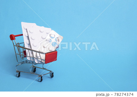 Pills in shopping basket on blue background Pills in shopping basket on blue background 78274374