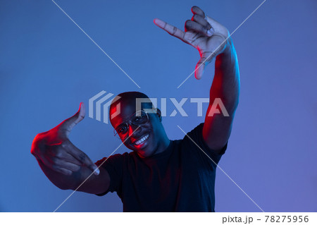 Portrait of young African handsome man posing isolated over dark background in mixed neon light. Portrait of young African handsome man posing isolated over dark background in mixed neon light. 78275956