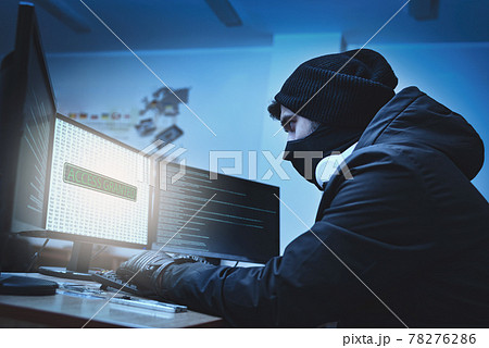 Side view of a hacker hacking into corporate data servers from his underground hideout. The place has a dark atmosphere, lots of displays Side view of a hacker hacking into corporate data servers from his underground hideout. The place has a dark atmosphere, lots of displays 78276286