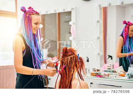 Woman hairdresser weaves to girl ginger dreadlocks. 78276506
