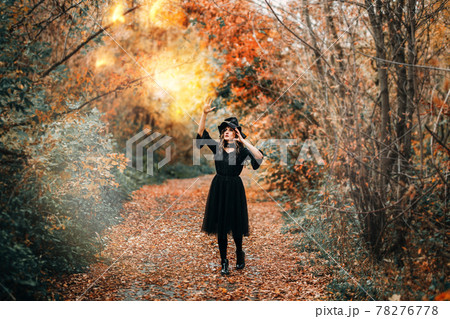 Girl dressed as witch casts fire spell in front of the forest Girl dressed as witch casts fire spell in front of the forest 78276778