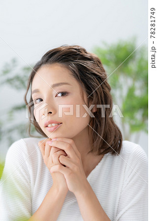 緑と黄色い花に囲まれて微笑む若い女性のポートレート 78281749