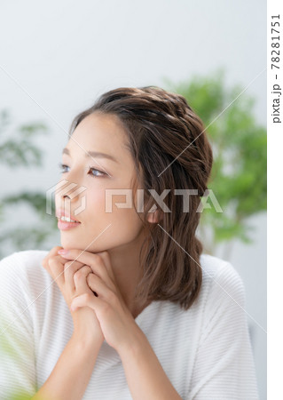 緑と黄色い花に囲まれて微笑む若い女性のポートレート 78281751