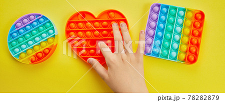 Kid hands playing with colorful pop It fidget toy. Colorful antistress sensory toy fidget push pop it. Kid hands playing with colorful pop It fidget toy. Colorful antistress sensory toy fidget push pop it. 78282879