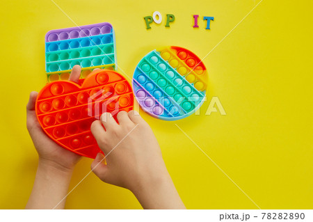 Kid hands playing with colorful pop It fidget toy. Colorful antistress sensory toy fidget push pop it. 78282890