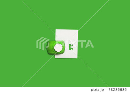 tiny hole puncher with a paper on a green surface 78286686