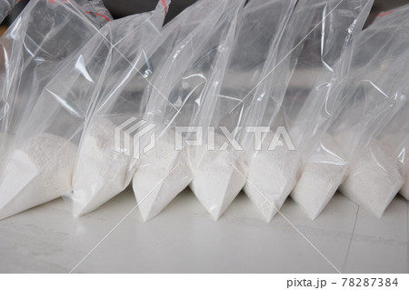 A large number of transparent sachets filled with white powder. White powder packaged in small sachets. 78287384