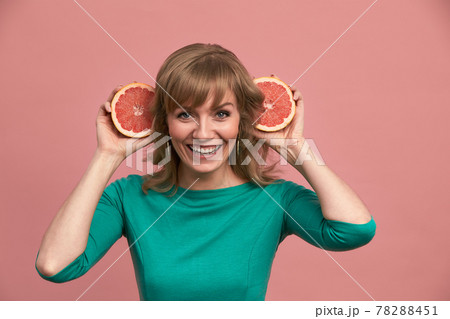 A beautiful girl with grapefruits in her hands, a blonde in a green dress holds halves of a grapefruit in her hands, beauty, vitamins, healthy skin. 78288451
