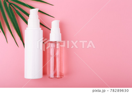 Cosmetic set with face cream and cleansing foam in transparent bottle on pink background with palm leaf and copy space 78289630