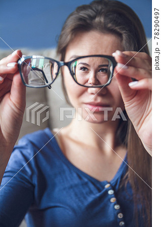 A woman with vision problems hold eyeglasses 78290497