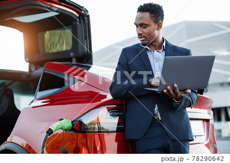 African businessman working on laptop and charging car African businessman working on laptop and charging car 78290642