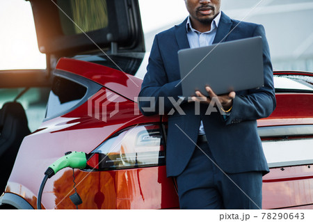 African man using laptop while recharge battery of car African man using laptop while recharge battery of car 78290643