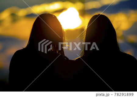 silhouette of two girls looking at the sunset. female hair against the setting sun. 78291899