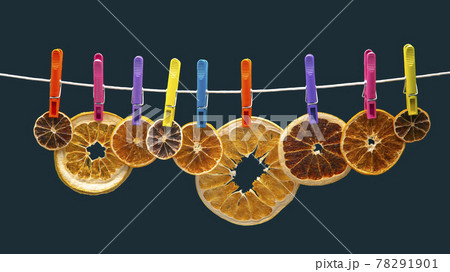 dried pieces of different citrus fruits hang on colored clothespins 78291901