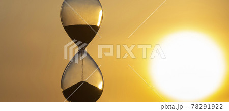 Hourglass counts time against the background of the evening setting sun Hourglass counts time against the background of the evening setting sun 78291922