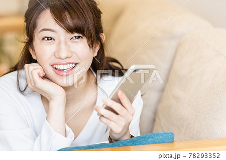 リビングのソファに寝そべってスマホの画面を見る女性 リビングのソファに寝そべってスマホの画面を見る女性 78293352